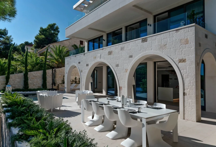 A modern and luxury Villa Acoona featuring a spacious patio and an outdoor dining area, surrounded by lush greenery on island Brac.