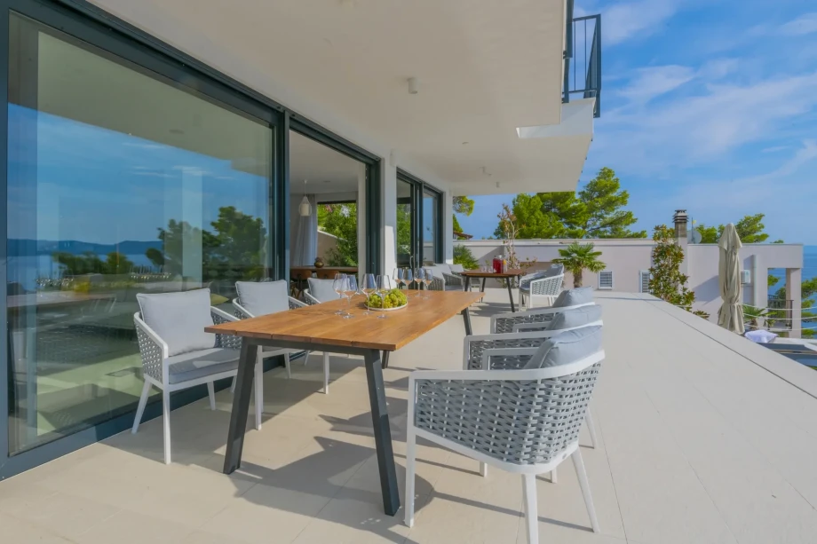 A stylish anteroom adorned with elegant tables and chairs, invitingly situated just before the charming glass-enclosed living room