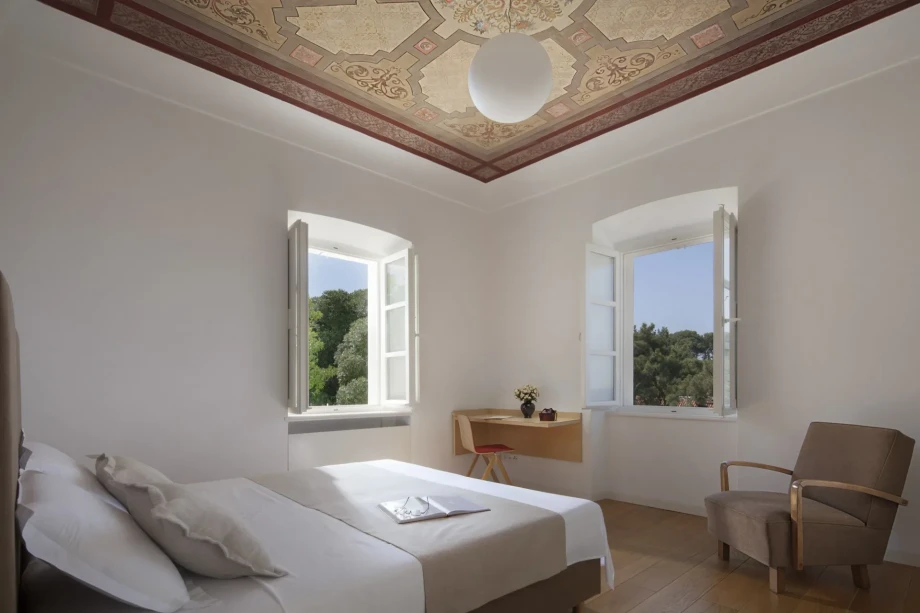 A spacious bedroom with two large windows, a large double bed and a beautifully decorated ceiling in a beautiful villa in Dubrovnik
