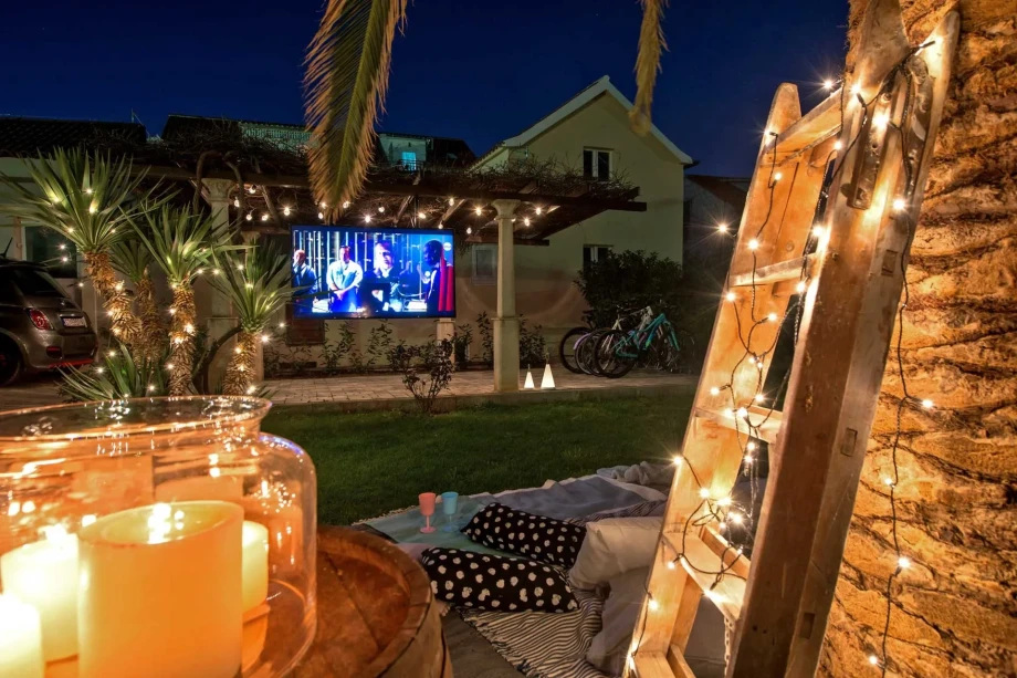 A charming backyard at Villa Sweet Home in Split Old Town, equipped with a TV and illuminated by soft candlelight.