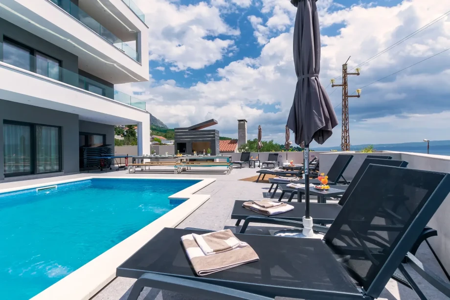 Outdoor seating area, sun loungers and heated pool in luxury villa Grande Divina with sea view