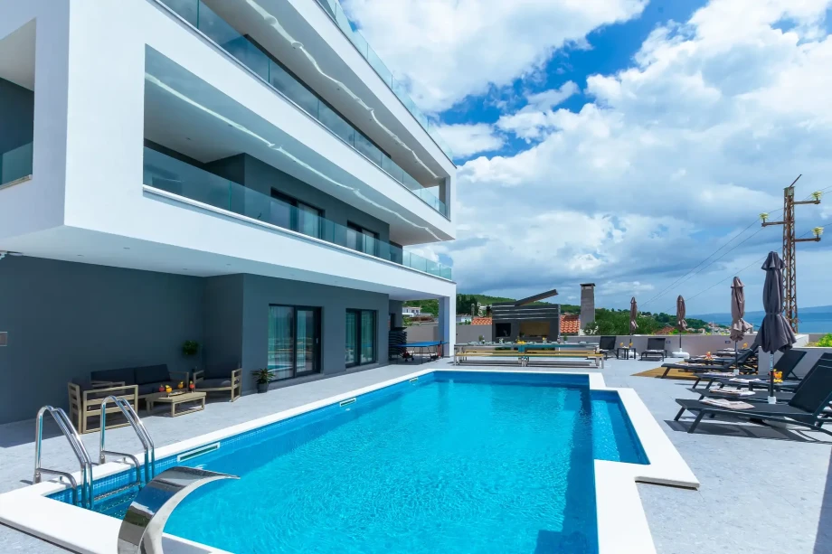 Private heated infinity pool with sun loungers and outdoor dining area in luxury private villa with sea view Grande Divina