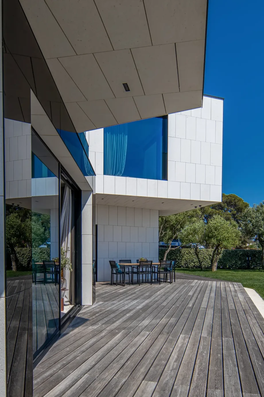 A porch with wooden flooring in front of the villa, featuring a table and chairs