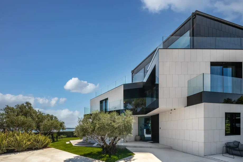 An olive tree that extends to the first floor of a villa with black and white tiles