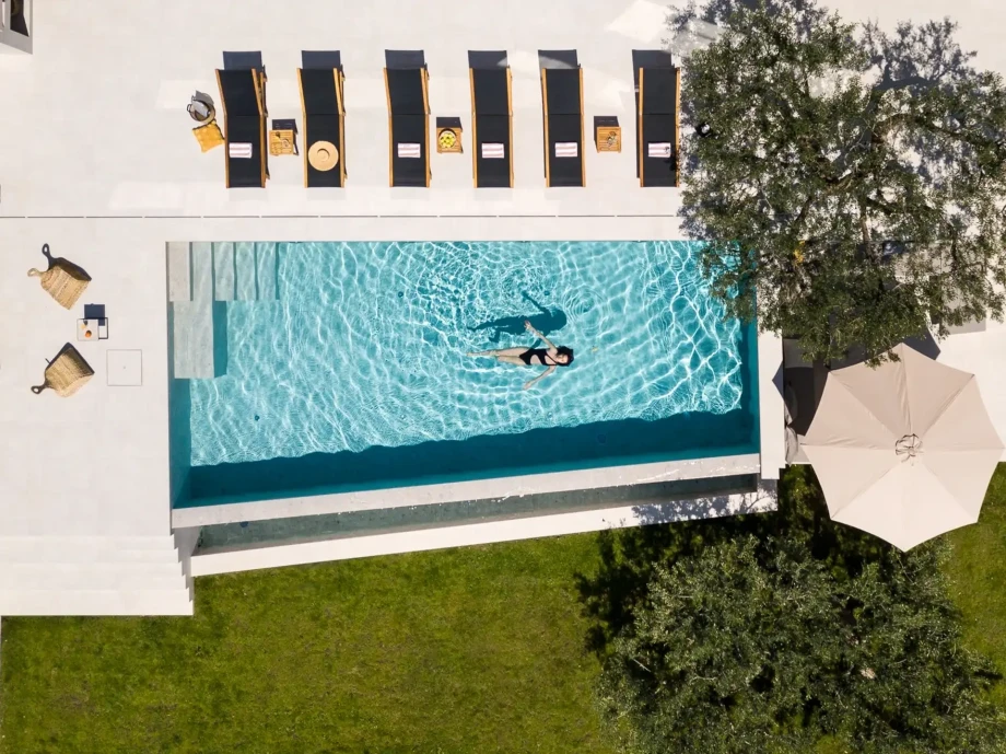 A beautiful woman is swimming in the pool in front of the luxurious Olive Tree Villa