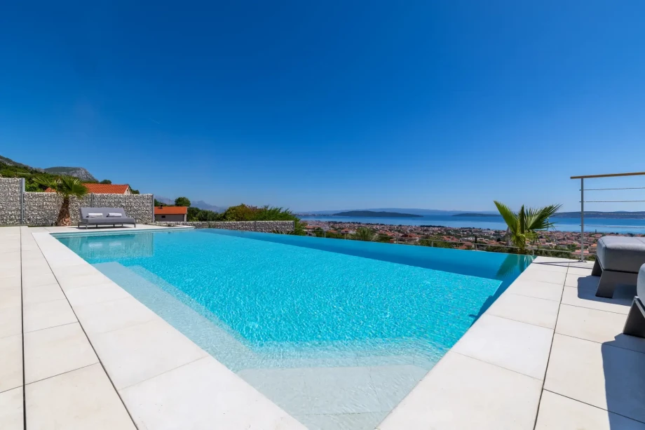 A large swimming pool at Villa Nikita, surrounded by a scenic view of the land and sea,