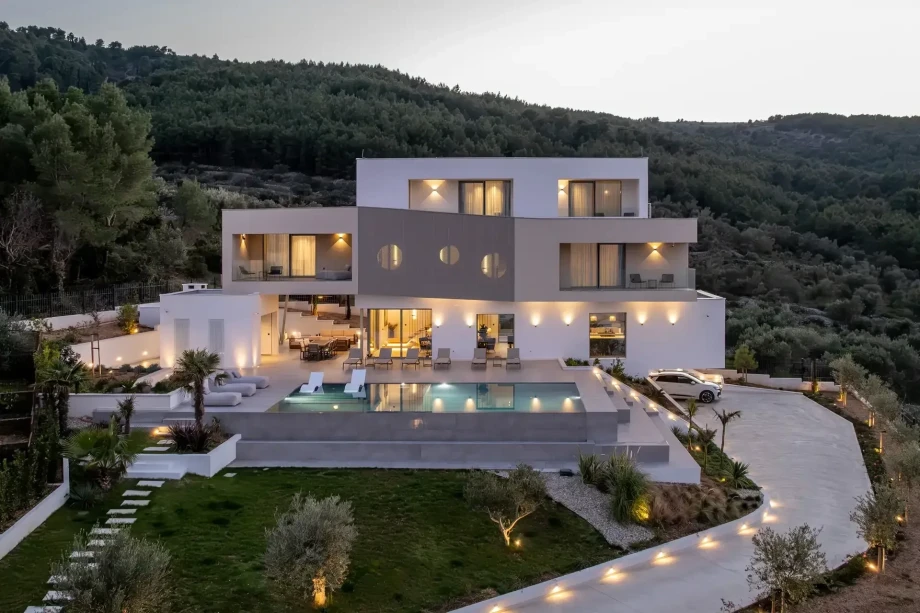 Dusk view of luxury villa Vista Maris near Trogir featuring a pool and landscaped garden.