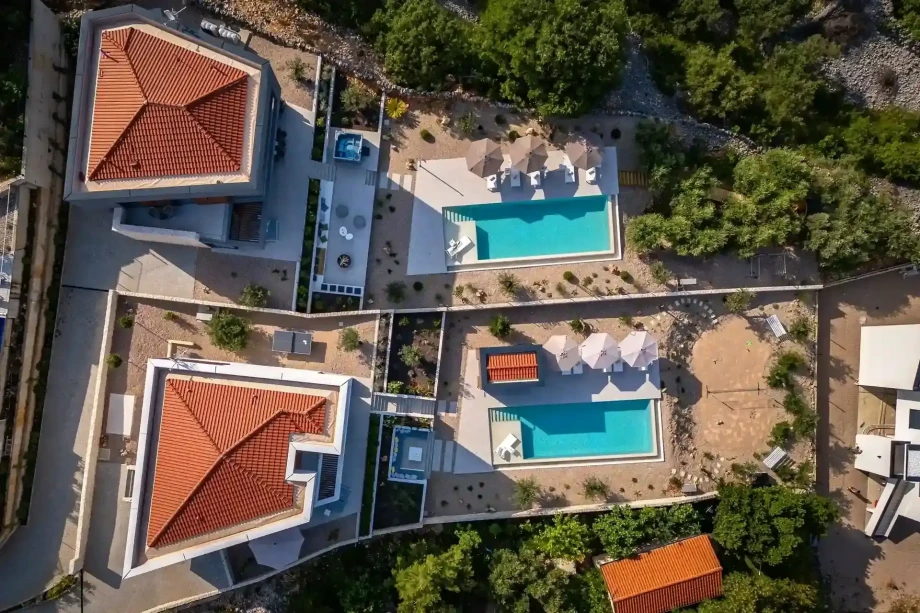 Aerial view of a villa Maravilla and Coralina featuring a large swimming pool surrounded by lush greenery and outdoor seating areas.