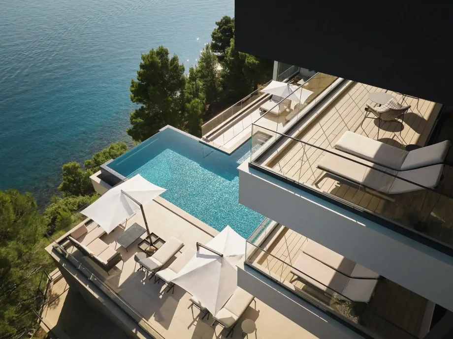 Exterior of luxury family villa Muse with outdoor heated pool, sun loungers, seating area and sea view