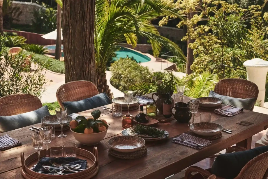 Dining table and chairs situated beneath a spacious tree by the luxurious Villa Rouge.