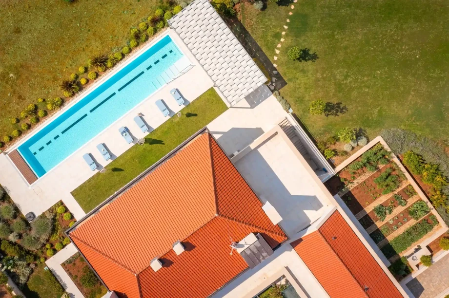 Aerial view of a luxury villa Hilltop Haven featuring a spacious swimming pool surrounded by lush greenery.