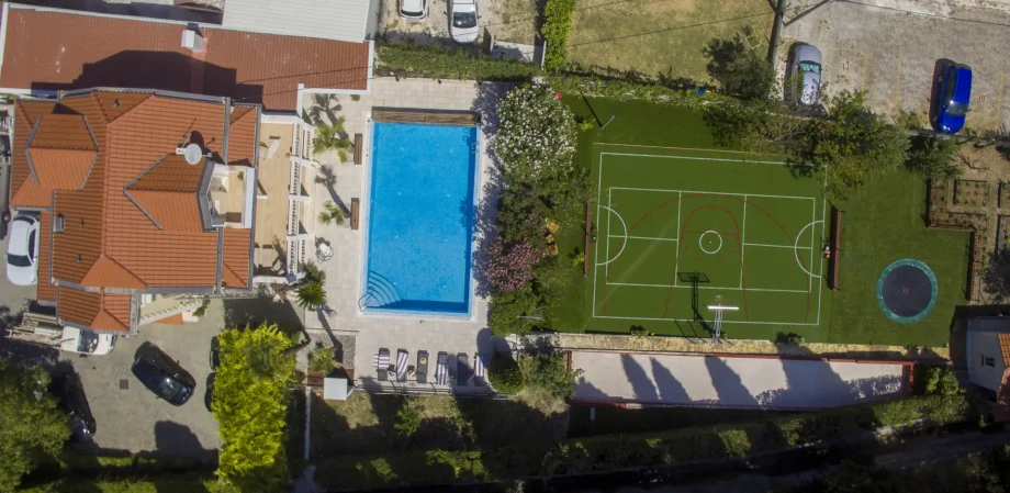 Aerial view of Villa Eterna in Split Kastela, featuring a house surrounded by a lush soccer field, ideal for family fun.