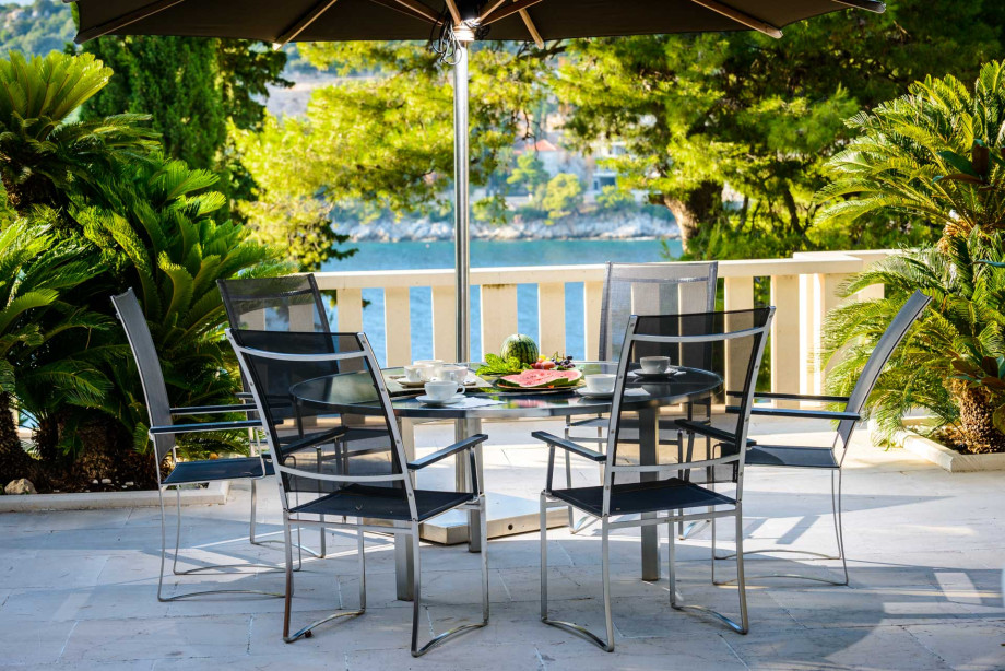 A dining table surrounded by chairs at Villa Royal Dubrovnik, highlighting a stylish and inviting atmosphere.